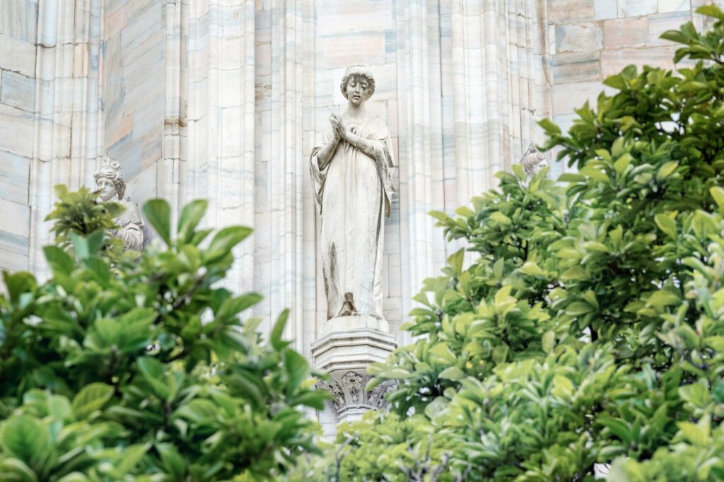 Monuments at facade of the italian Cathedral of Milano, Duomo. Sculpture of woman on church exterior